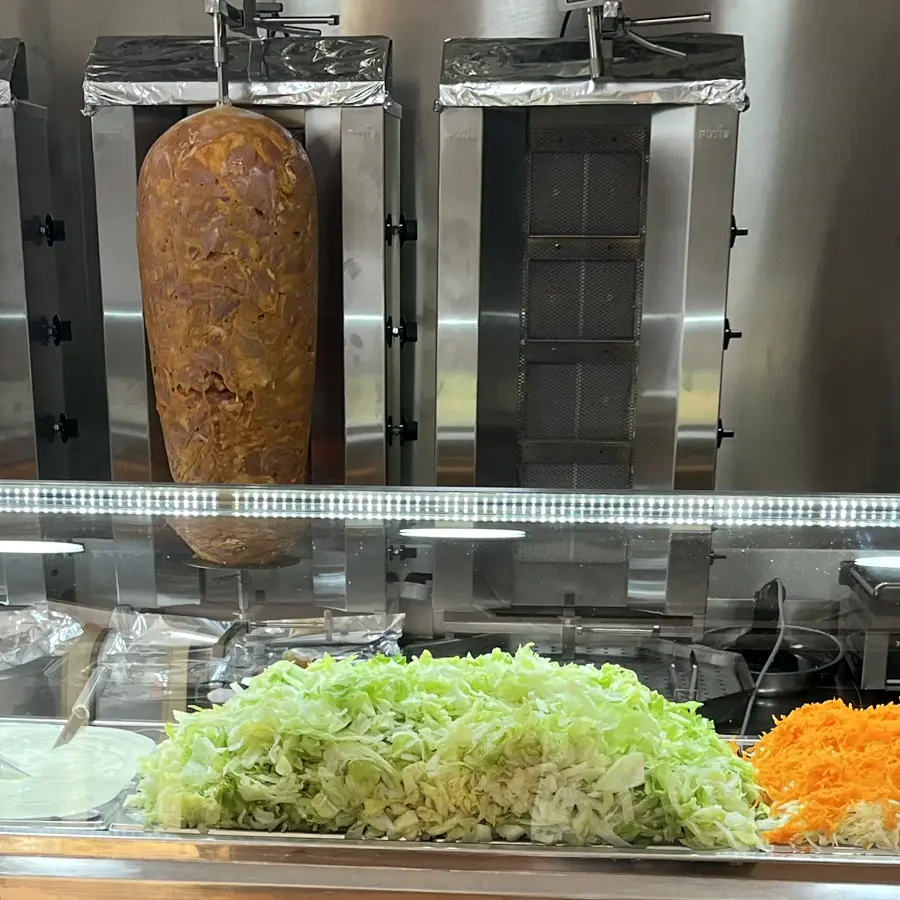 La barra con tres asadores de kebab y las bandejas de verdura